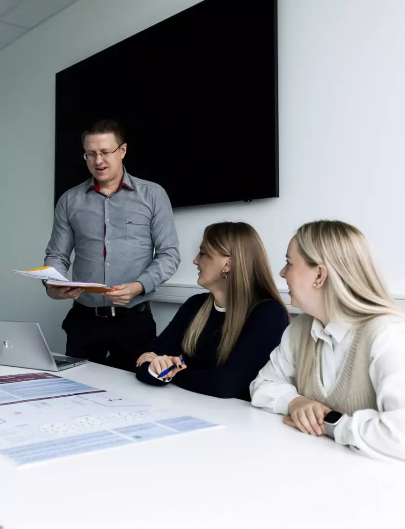 In a small, modern lecture space, students engage in a discussion on business development strategies led by a lecturer. The close-knit learning environment encourages active interaction and deep topic exploration.